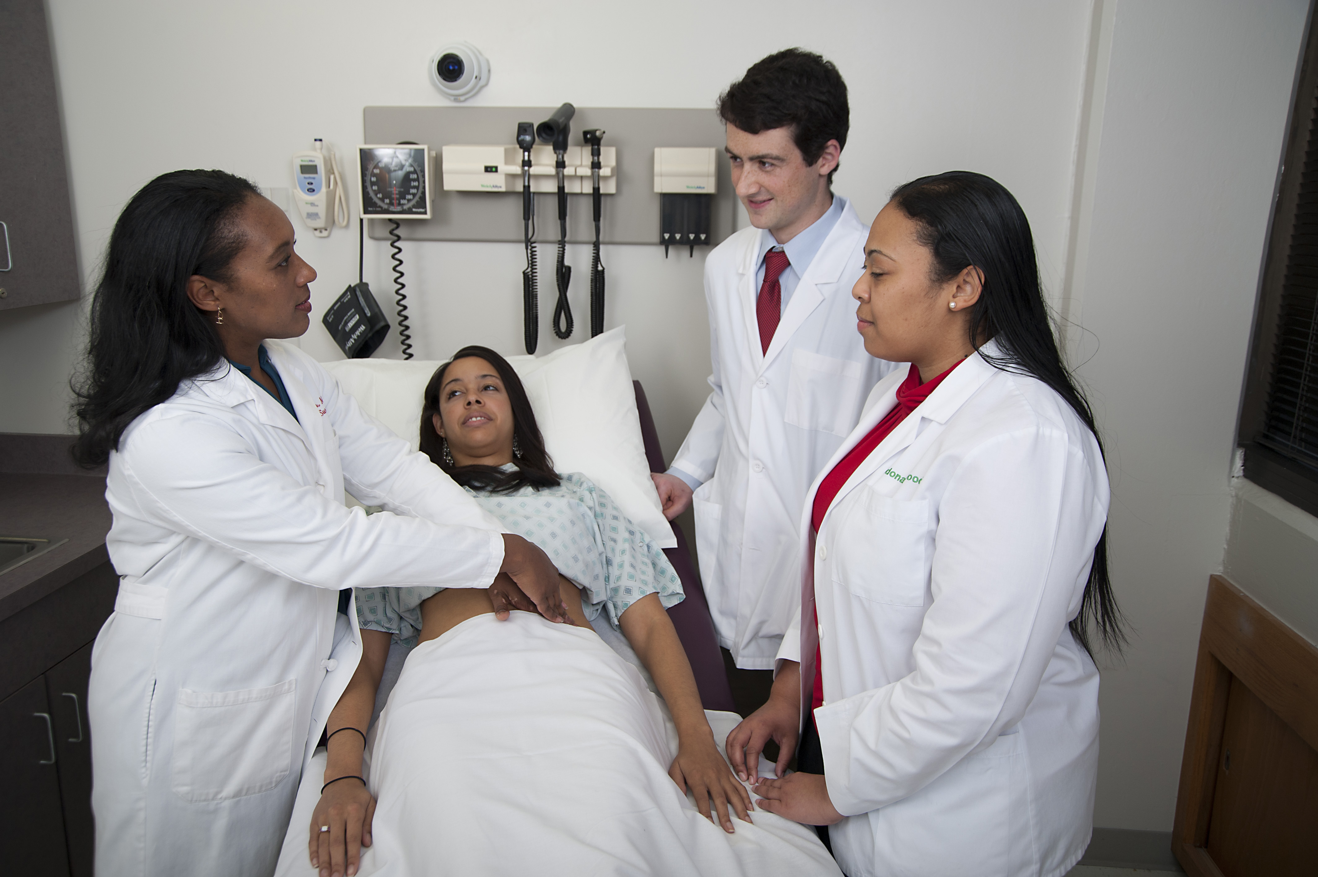 Abdomen Exam two students observe as a faculty person demonstrates the abdominal exam on a standardized patient