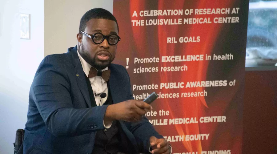 Man seated in front of Research Louisville banner