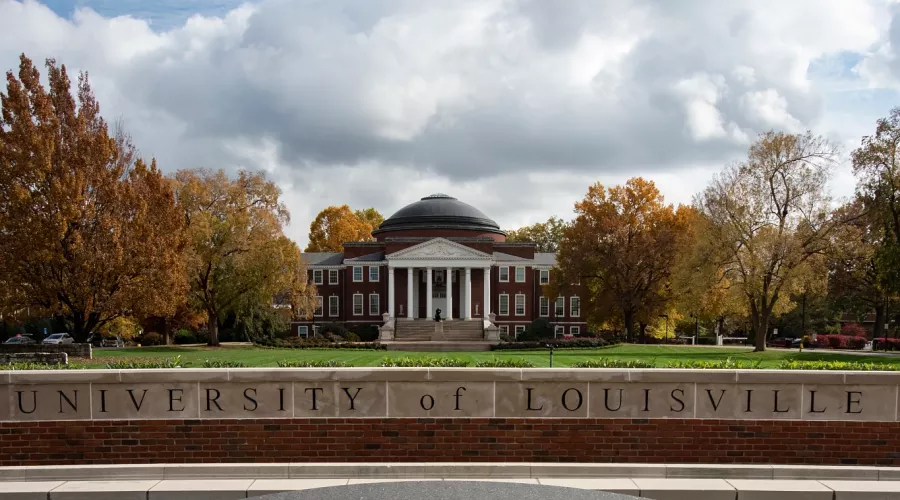Wide-angle portrait of the exterior of Grawemeyer Hall and the Oval with the 3rd Street entrance sign and Minerva in the foreground