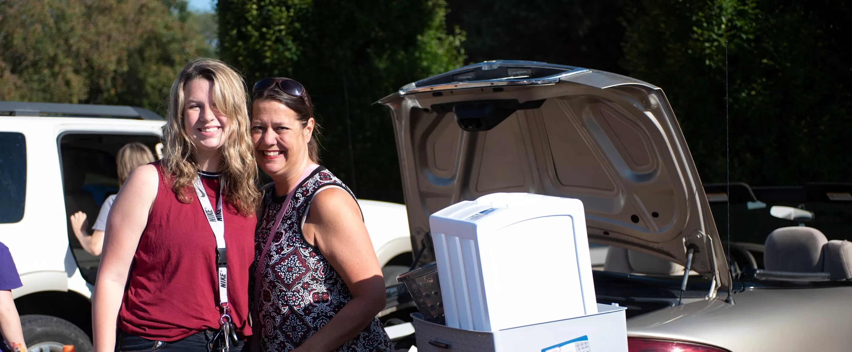 Mom and daughter pose for a photo between loading items into their move in box.