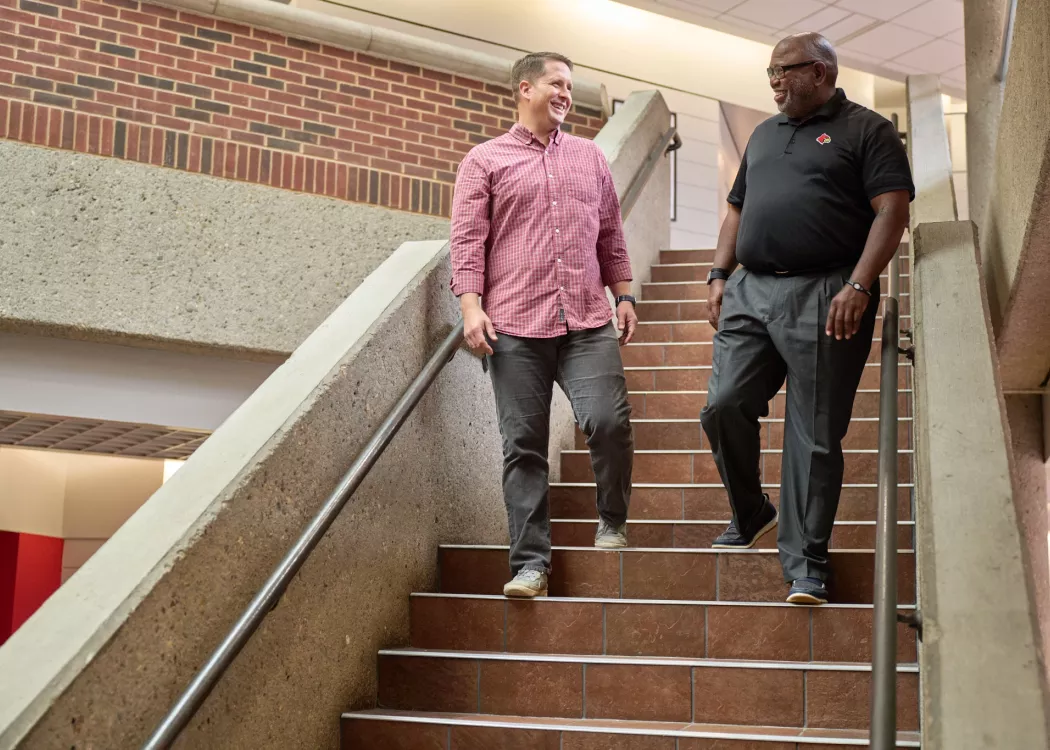 Professor Wade walking down the steps and talking with a student in the college of business.