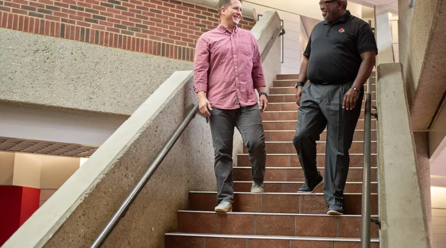 Professor Wade walking down the steps and talking with a student in the college of business.