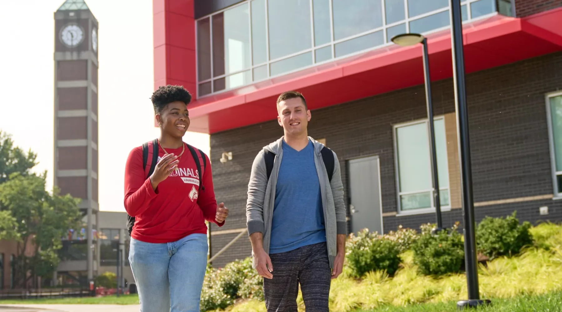 Two students walking by Belknap Residence Hall with the clock tower in the background.