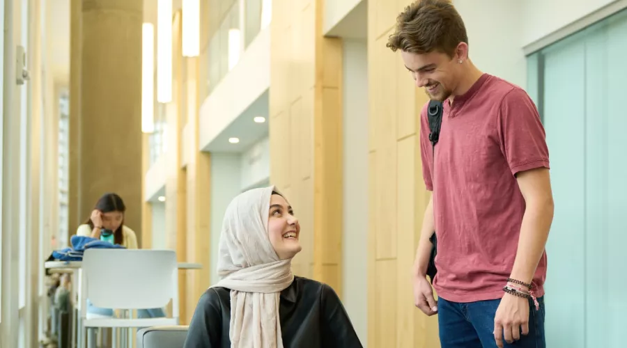 Two students talking over what is on the laptop screen.
