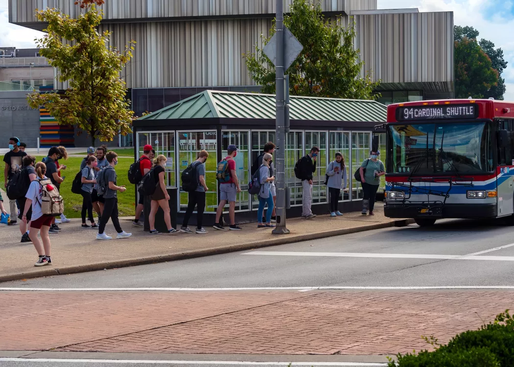 Students waiting for a Cardinal Shuttle with the Speed Art Museum in the background