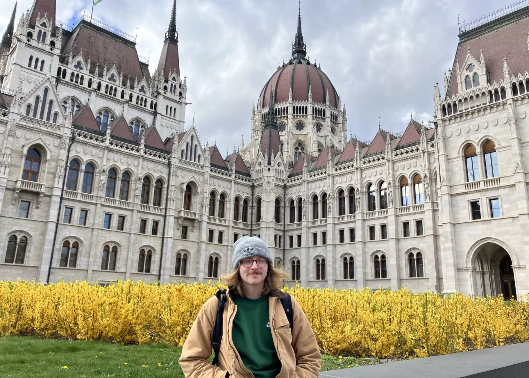 UofL student stands in front of yellow flowers and the Hungarian Parliament building in Budapest.